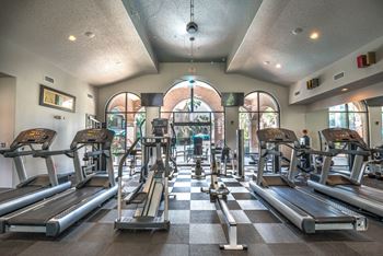 a gym with cardio machines and weights on a checkered floor